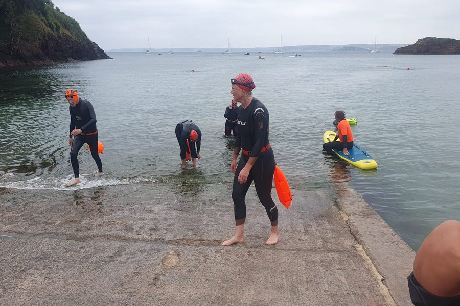 Participants running and swimming along the Hope Cove coastline.